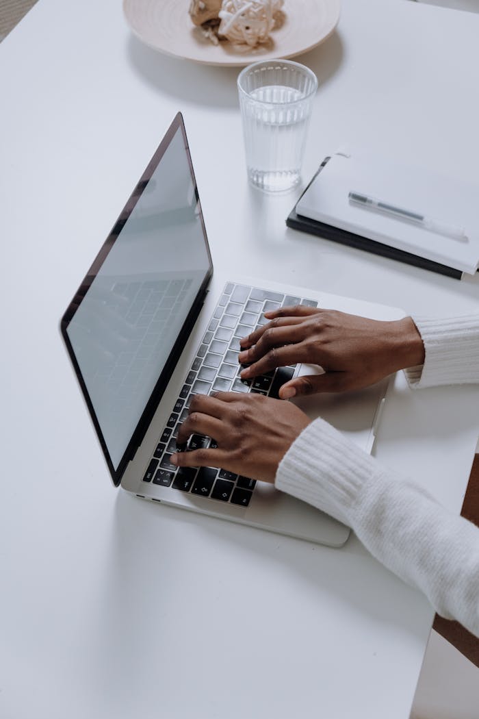 hero A woman typing on a laptop at a minimalist, modern home office desk, showcasing productivity.